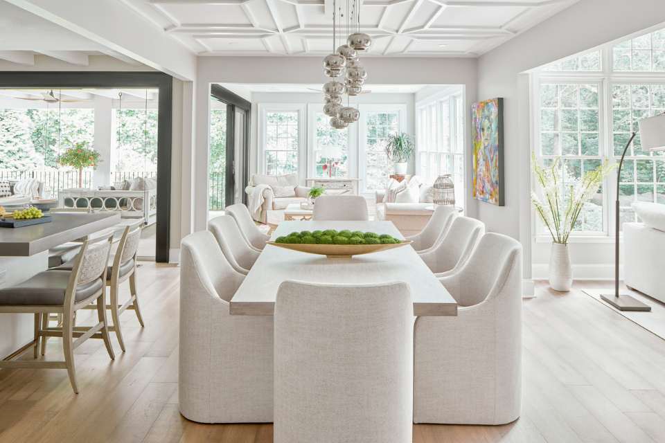 open concept designer modern home with white dining room seating, statement lighting and large pocket doors to porch